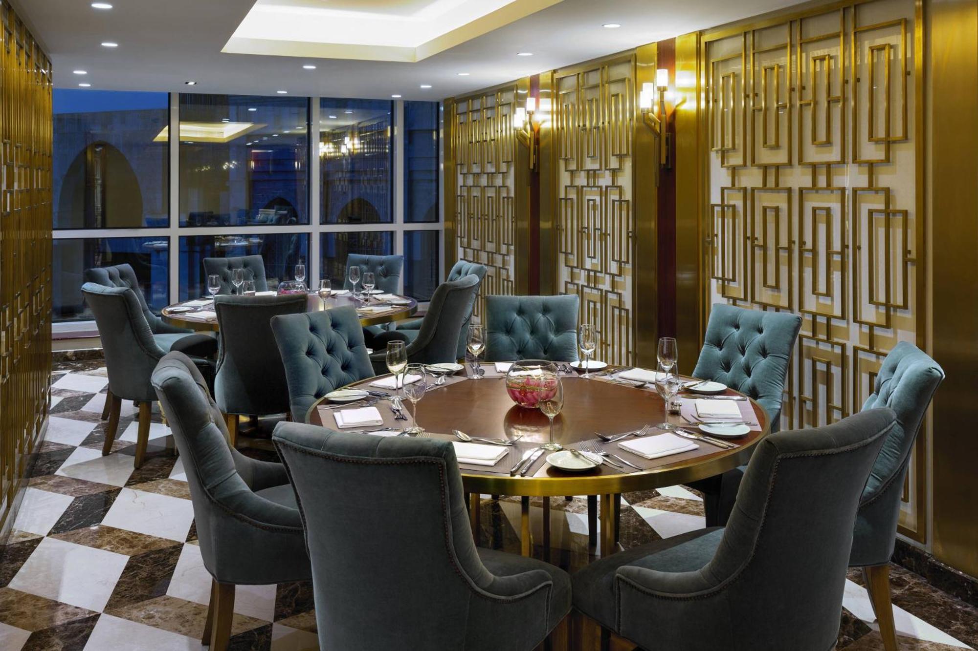 Sheraton Makkah Jabal Al Kaaba Hotel Mecca Exterior foto The photo shows an elegant dining room with a sophisticated ambiance. It features a round wooden table at the center, surrounded by plush chairs upholstered in a soft, teal fabric. The room has a stylish décor, highlighted by a geometrically patterne
