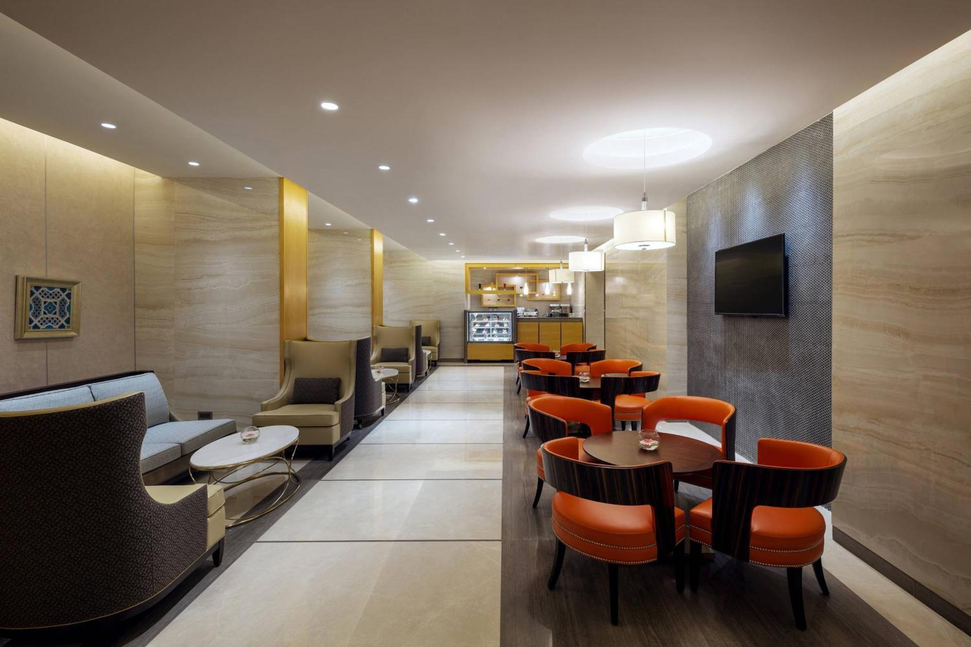 Sheraton Makkah Jabal Al Kaaba Hotel Mecca Exterior foto The photo depicts a modern and elegant lounge or café area. The interior features soft, warm lighting and a combination of neutral and bold color schemes. On the left side, there are comfortable seating arrangements with light-colored sofas and chair